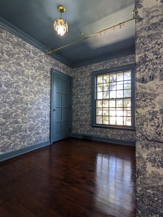 newly stained wooden floor in a bedroom with blue patterned wallpaper