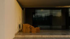 A balcony space with a woven chair and foot rest