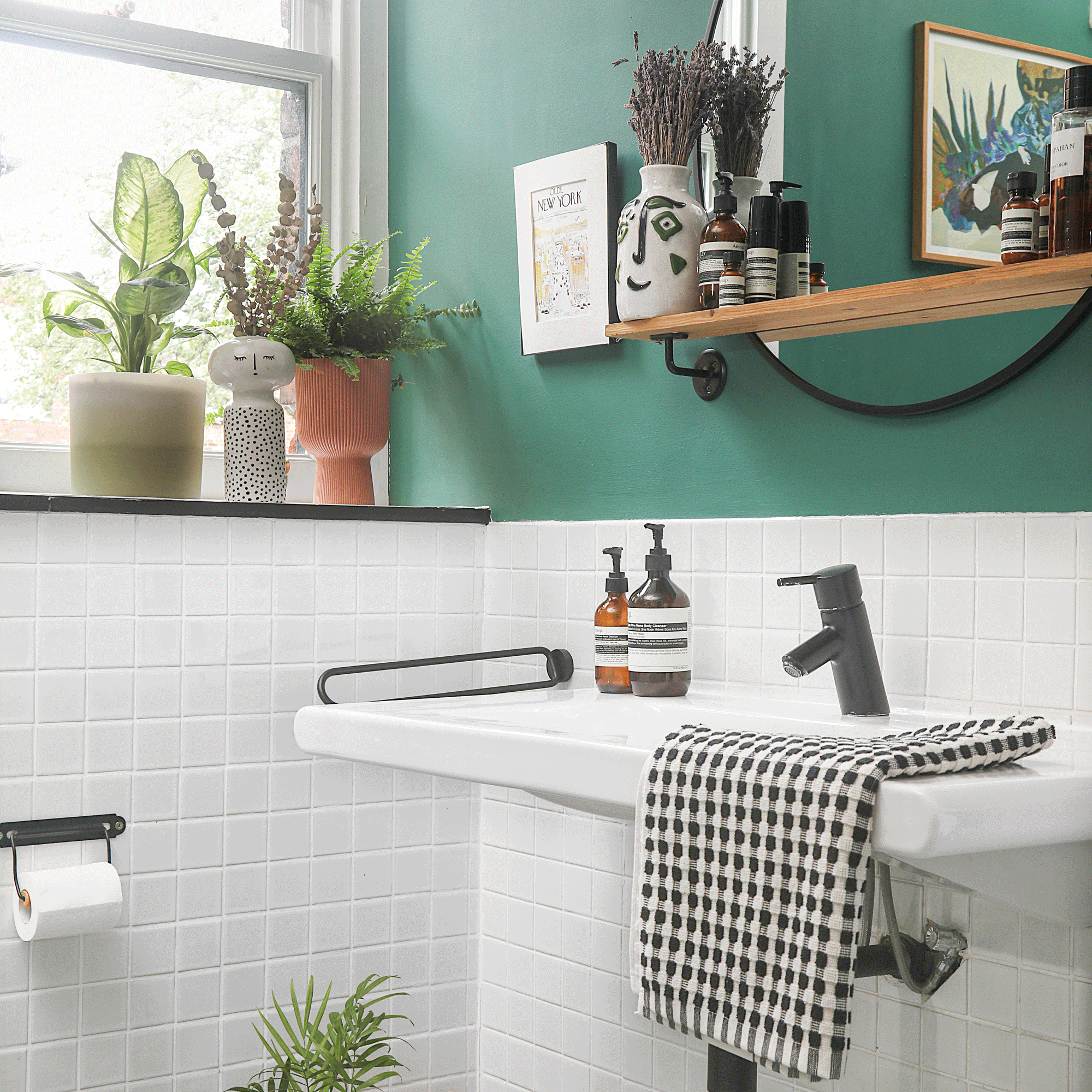 green bathroom with a black and white towel and white basin with black fixtures