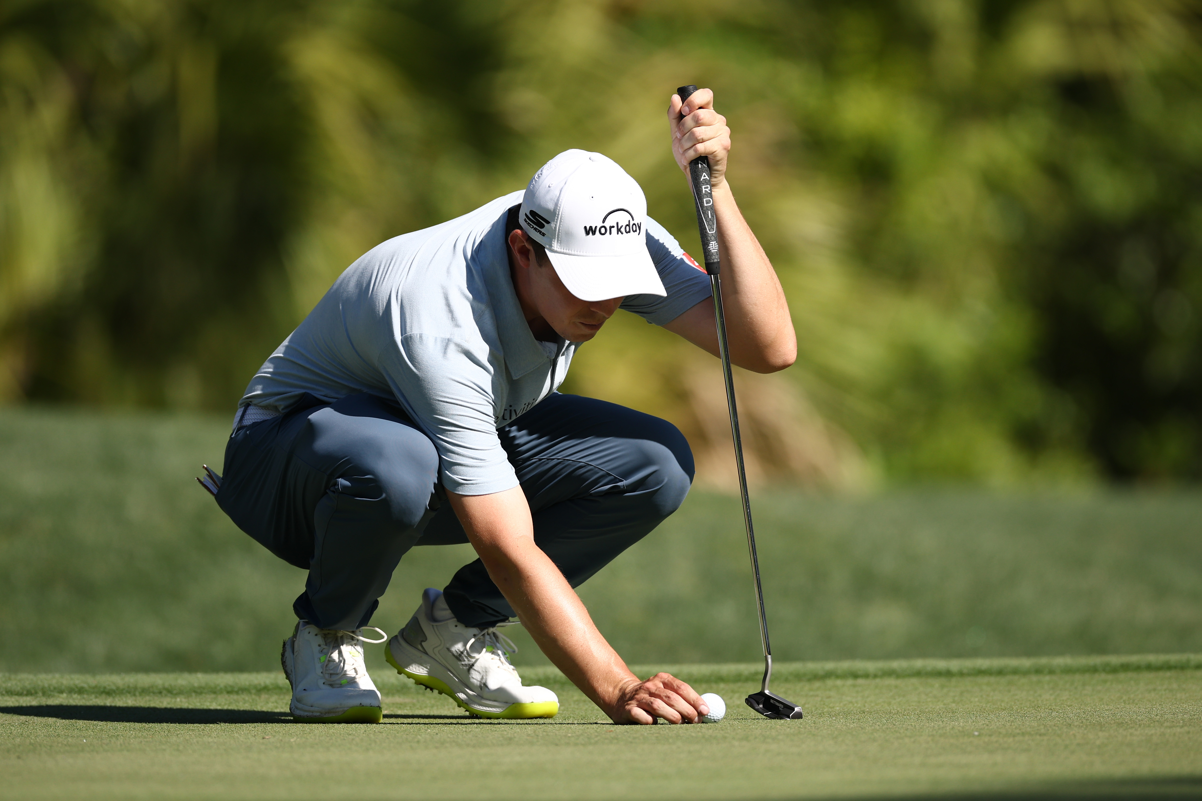 Matt Fitzpatrick lines up a golf ball on the green