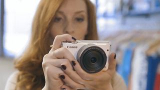 Canon EOS M10 being held by a photographer inside a clothing store