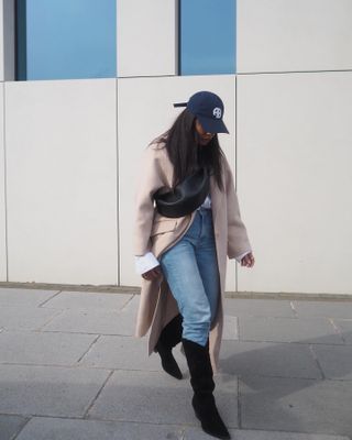 Woman wears wool coat, blue jeans, black cowboy boots