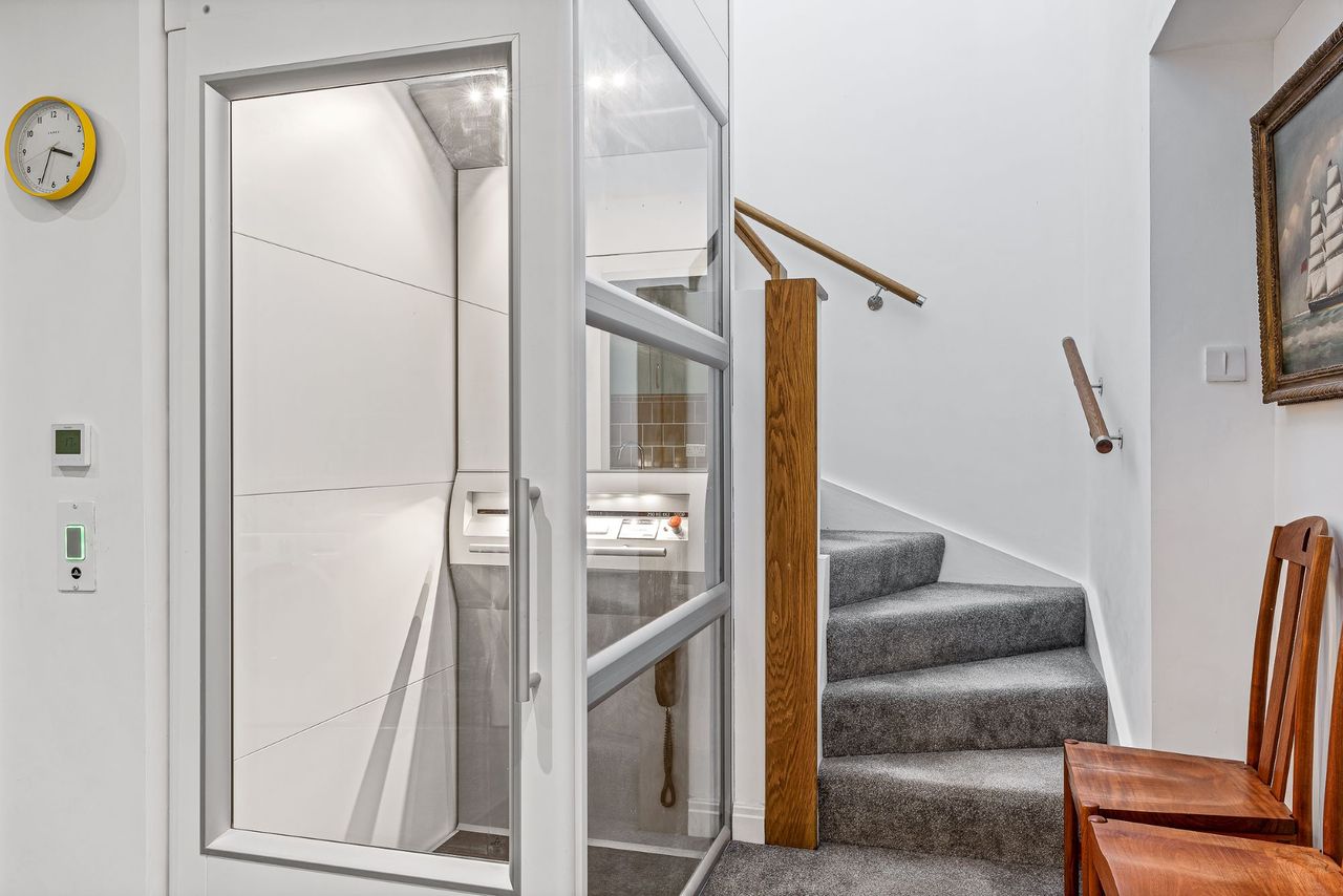 The stairs upstairs wrap around a glass lift which leads to the first floor