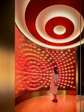 Person stands within circular red-lit column in Ya-man Tokyo store