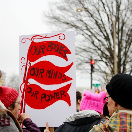 Crowds of women and men holding protest signs march through the streets during the Women's March on Washington, D.C.. Prominent sign says, "Our Bodies, Our Minds, Our Power." Protest. March. Community. Togetherness.