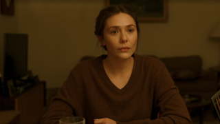 Elizabeth Olsen at a table in His Three Daughters