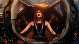 a woman in a black tank top looks fearful inside a glass-lined cockpit while piloting a spacecraft as other spaceships explode behind her