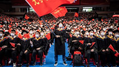 Chinese students from the Huazhong University of Science and Technology wave flags during a graduation ceremony 