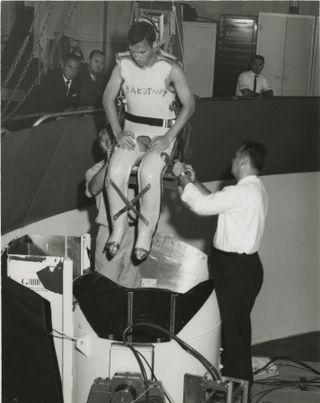 John Zakutney, a participant in joint weightlessness research from NASA and the U.S. Naval School of Aviation Medicine, is lowered down into a centrifuge pod.
