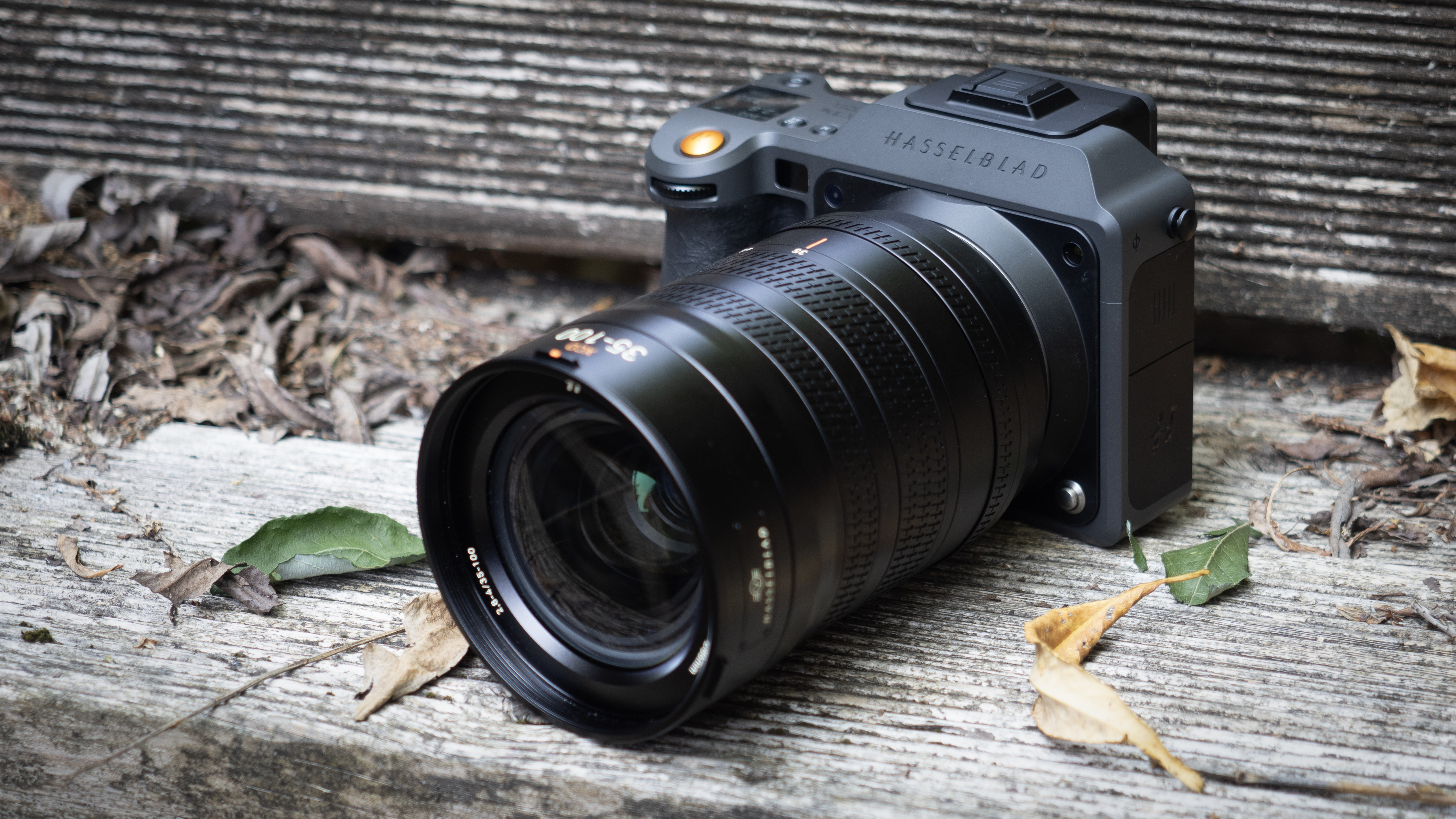 Hasselblad X2D II 100C with Hasselblad XCD 35-100E on a wooden surface, in an outdoor setting