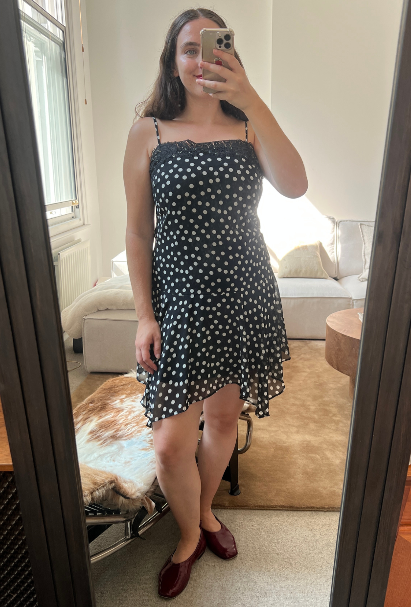 An image of Who What Wear UK fashion writer, Ava Gilchrist, wearing the viral M&S polka-dot lace-trim slip dress. She is a size M and wears it in a size 10.