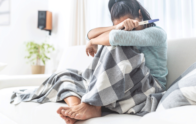 Woman looking upset after taking a pregnancy test