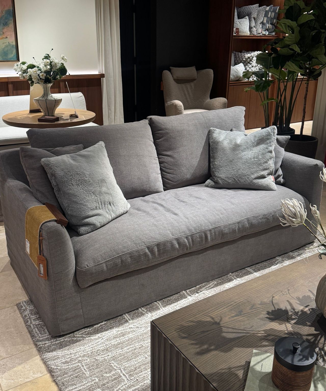 gray sofa with cushions on gray rug with timber coffee table