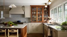 Kitchen with lower oatmeal cabinets and upper cabinets and the island in a warm wood