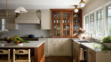 Kitchen with lower oatmeal cabinets and upper cabinets and the island in a warm wood