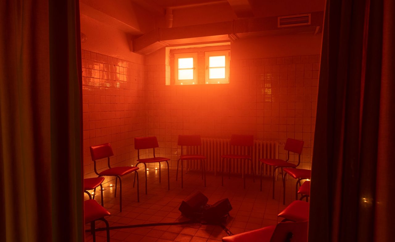 tiled room with empty chairs and red light: from ‘Tell Them I Said No’ festival at E-WERK Luckenwalde