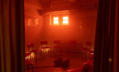 tiled room with empty chairs and red light: from ‘Tell Them I Said No’ festival at E-WERK Luckenwalde