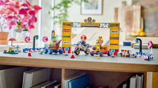 Lego Mario Kart figures, karts, and course scenery laid out on a wooden surface