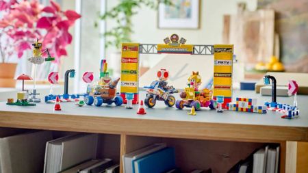 Lego Mario Kart figures, karts, and course scenery laid out on a wooden surface