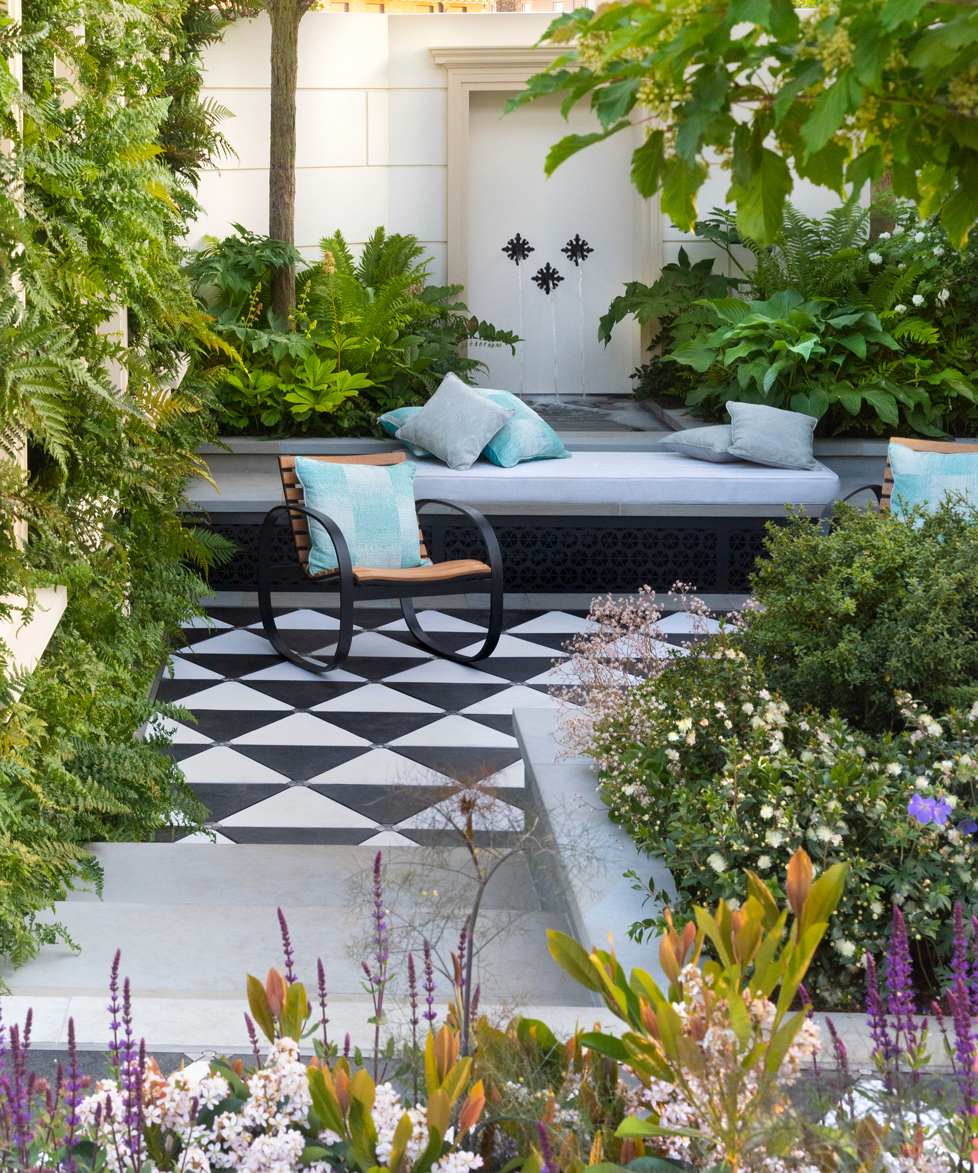 A tiled terrace with ferns and a padded garden bench