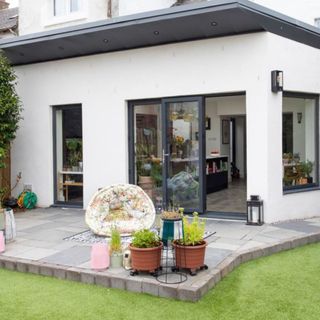 Single storey extension with grey roof, window frames and white rendered exterior