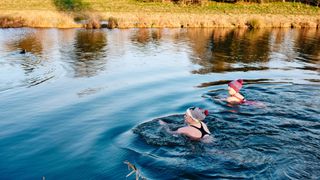 Two women swimming out in open water for exercise
