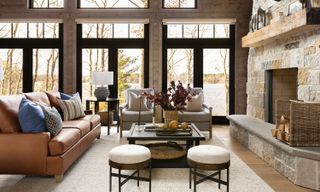living room with leather sofa and fireplace and picture windows and views of trees and lake