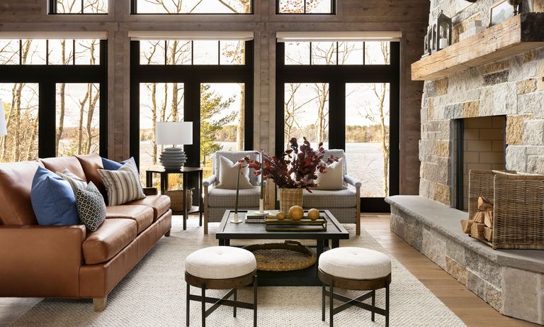 living room with leather sofa and fireplace and picture windows and views of trees