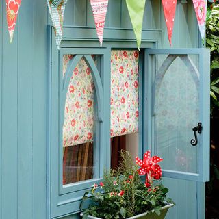 garden shed coloured blue with plants and bunting flags