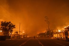 A man watches the flames from the Palisades Fire burning homes on the Pacific Coast Highway amid a powerful windstorm on January 8, 2025 in Los Angeles, California. 