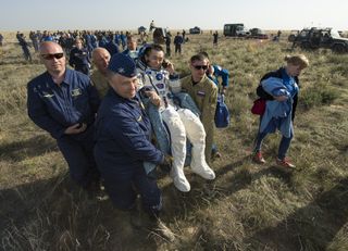 Expedition 39 Commander Koichi Wakata of the Japan Aerospace Exploration Agency (JAXA) is carried in a chair to a medical tent after returning to Earth aboard a Russian Soyuz TMA-11M spacecraft.