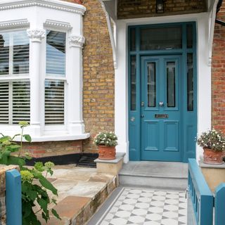 house exterior with white window and teal door and bricked wall