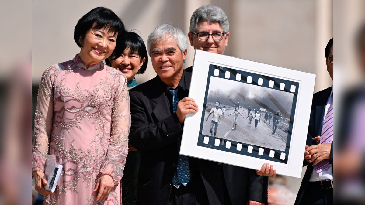 Vietnamese-US photographer Nick Ut (C) holds his Pulitzer and World Press Photo Award, 1972 photograph &#039;Napalm Girl&#039;, depicting Kim Phuc (L) as they attend Pope Francis&#039; weekly open-air general audience in St. Peters&#039; square on May 11, 2022 at the Vatican