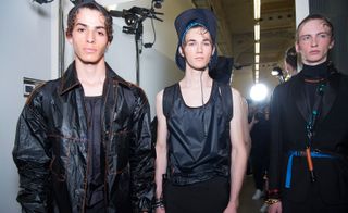 3 male models in dark clothing & hats