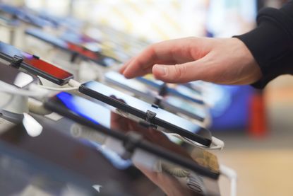 Hand of male buyer testing smartphone in electronics store 