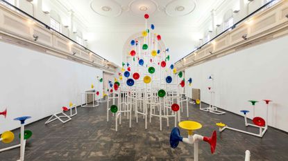 Installation in a former church made out of white pipes and colourful funnels