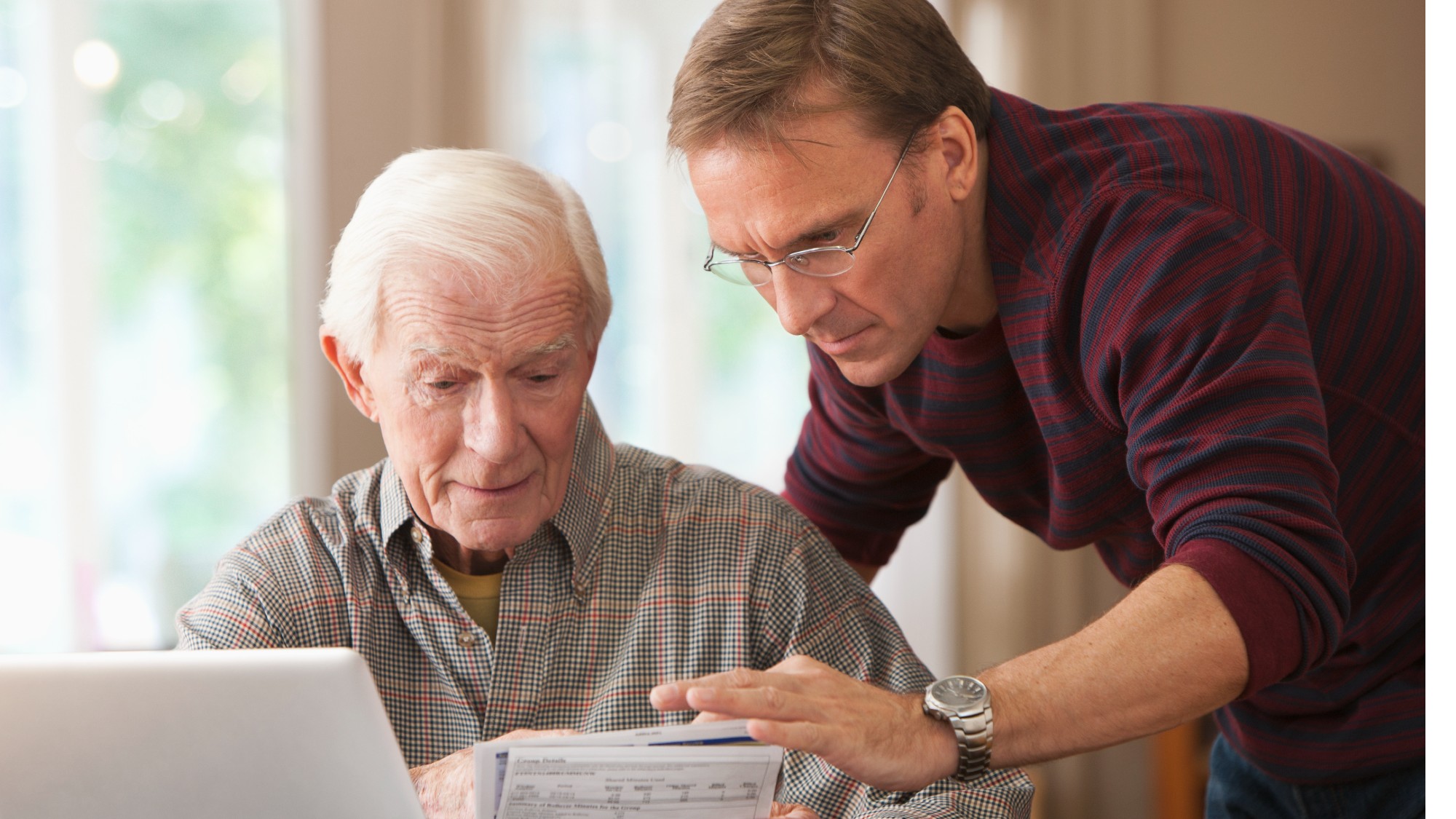 Son helping his senior dad with his finances on the computer
