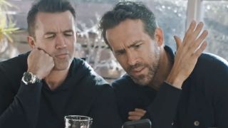 Ryan Reynolds and Rob Mcelhenney sitting at a bar and looking at a cellphone in the Docuseries Welcome to Wrexham.