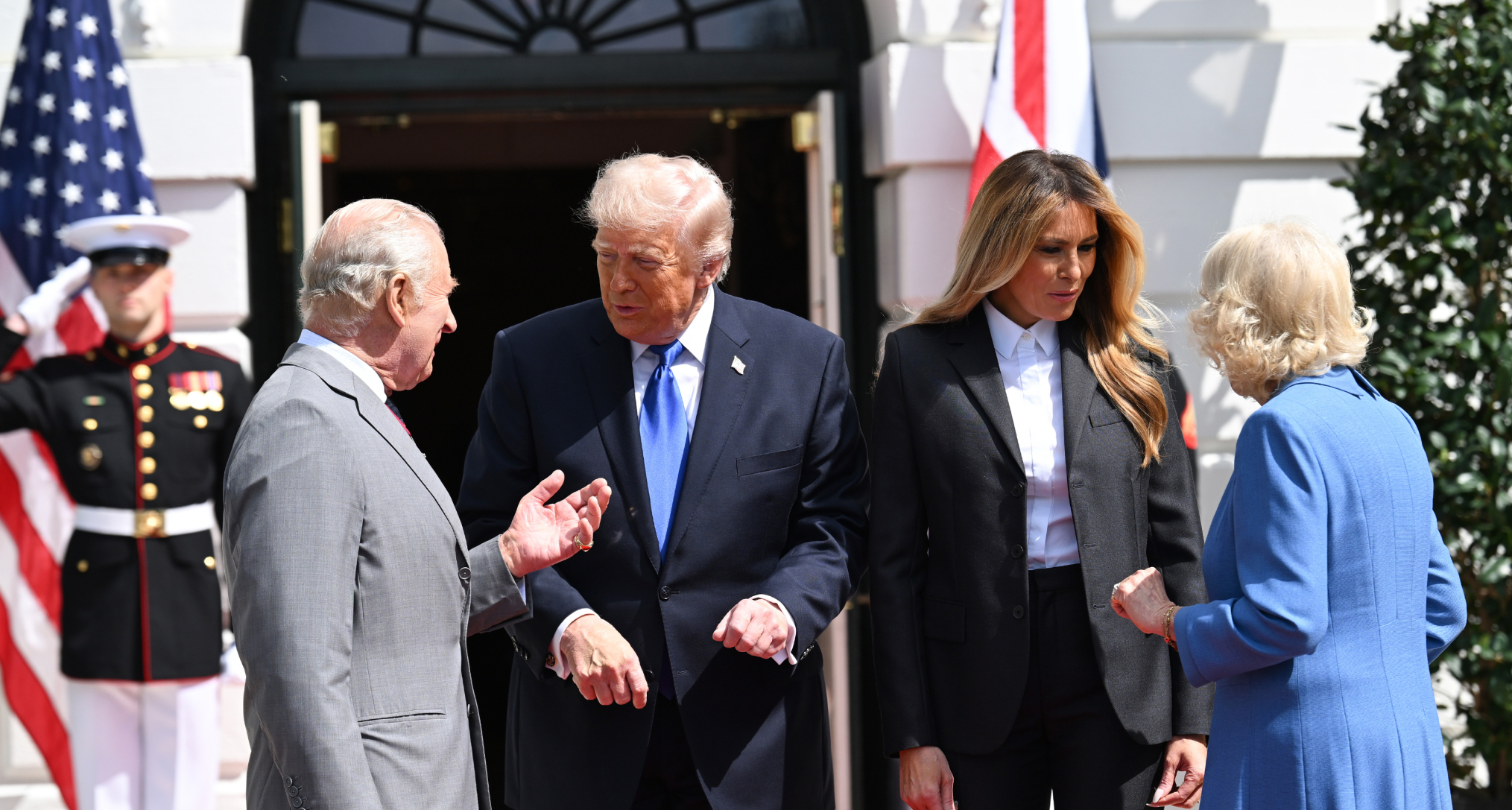 King Charles, Donald Trump, Melania Trump and Queen Camilla talking in front of flags