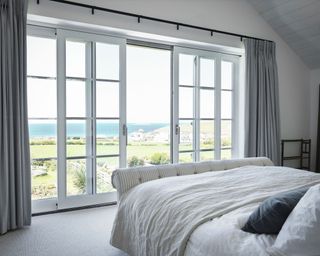 White bedroom with floor to ceiling doors in Cornish coastal newbuild
