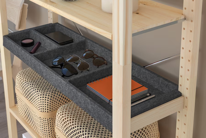 Close up of a wooden IKEA IVAR shelving unit with a felt shelving insert with different compartments