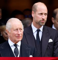 King Charles and Prince William wearing black suits and ties standing next to each other