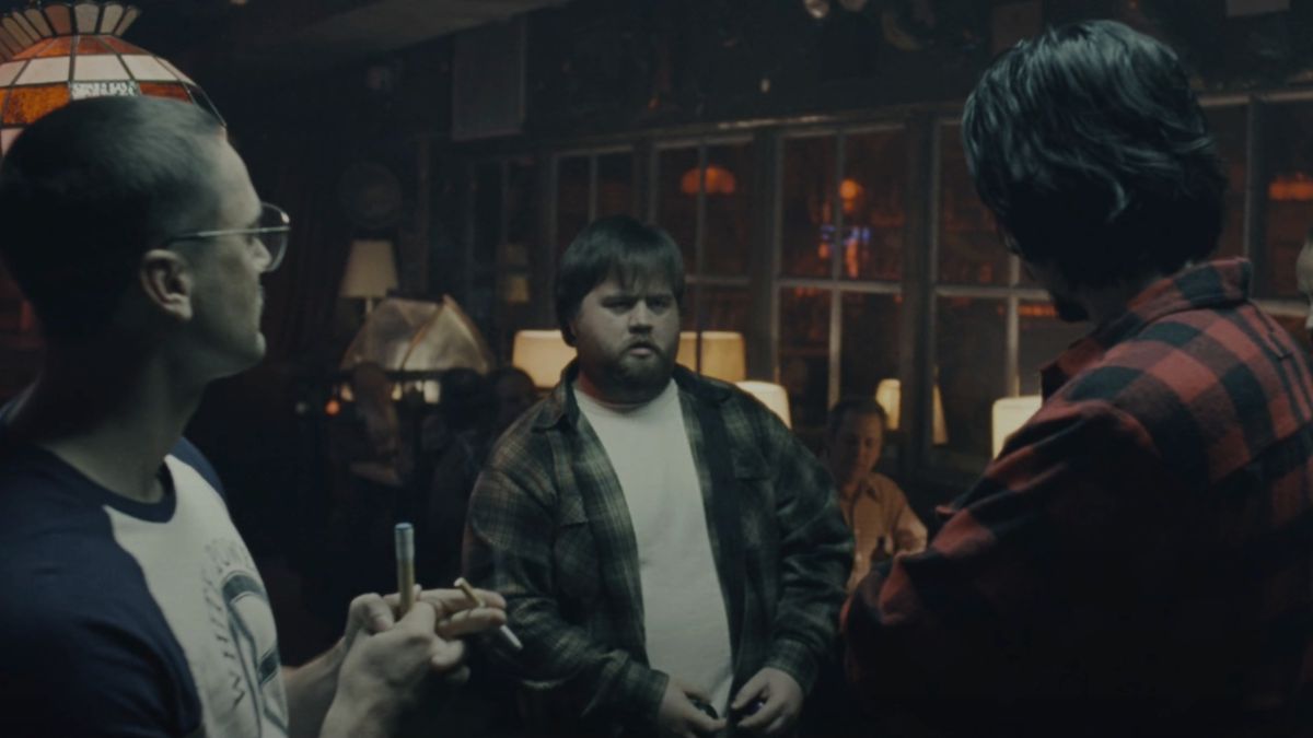 Paul Walter Hauser stands in the middle of a group of guys playing pool in BlacKkKlansman.