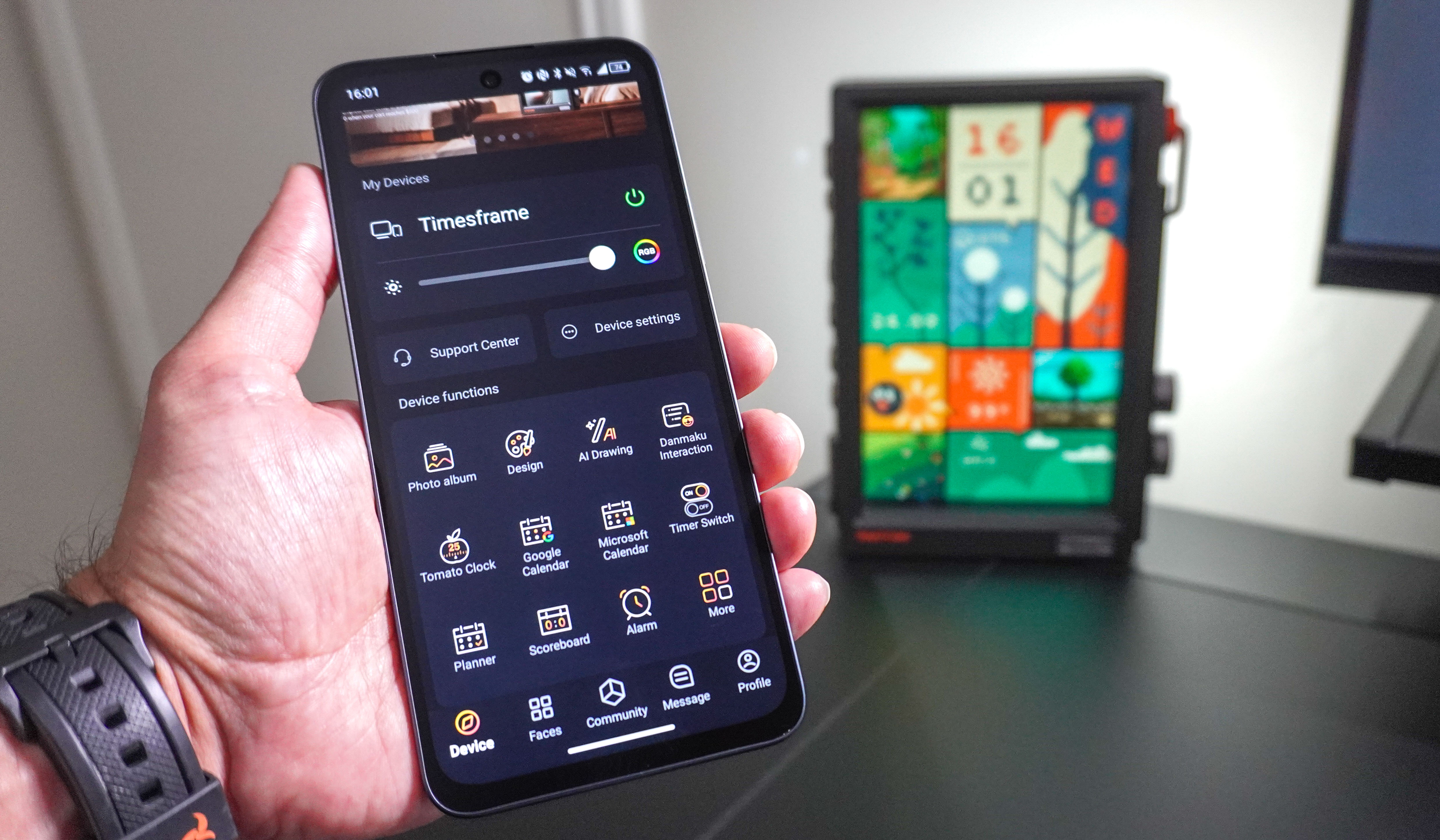 A person using the Divoom app on a phone to adjust the settings of the Divoom Times Frame
