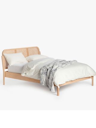Rattan Bed with off-white bedding and grey throw lying on bed