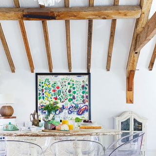 White dining room in barn with exposed wooden beams on ceiling