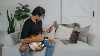Man plays a hollowbody guitar on the sofa