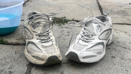 Dirty grey and white sneaker beside a freshly cleaned white sneaker sitting on a outdoor stone patio next to a washbasin.