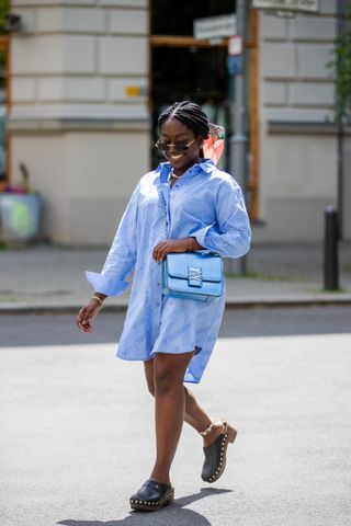 BERLIN, GERMANY - MAY 25: Lois Opoku is seen wearing blue oversized button shirt with logo print Karl Lagerfeld, bag Karl Lagerfeld, clogs - Bally, sunglasses Cartier, scarf Salvatore Ferragamo on May 25, 2021 in Berlin, Germany. (Photo by Christian Vierig/Getty Images)