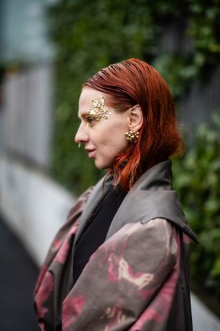 woman with red hair and gold face paint